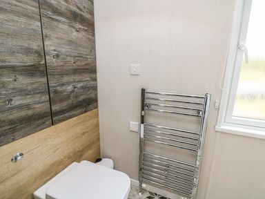 A bathroom with a toilet next to a towel radiator and a window at Meadow Retreat in Nantmel near Rhayader