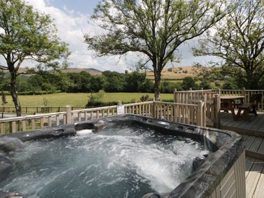 An outdoor area with a hot tub and a wooden table at Meadow Retreat Nantmel near Rhayader