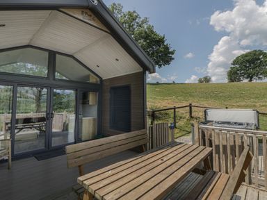 An outdoor area with a table, chairs and hot tub at Meadow Retreat in Nantmel near Rhayader