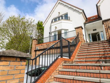 Stairs leading up to a white building with red roof and black railings at Seashells in Tenby