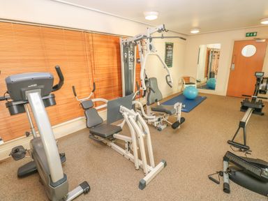 A gym room with exercise bikes weight machines a rowing machine a blue exercise ball and a blue mat at Seashells in Tenby
