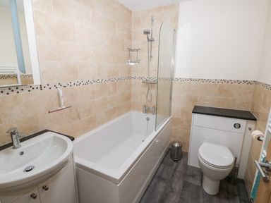 A bathroom with a bathtub shower combination sink and toilet at Elliotts Retreat in Sheringham