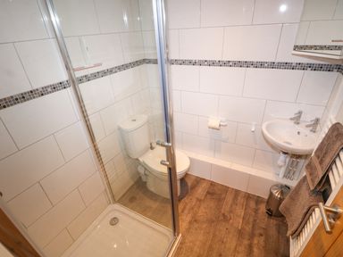 A bathroom with a shower enclosure toilet sink and towels at Elliotts Retreat in Sheringham