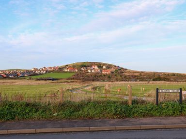 A street view with green fields and houses on a hill in the background at Elliott's Retreat in Sheringham