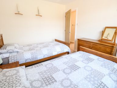 A bedroom with two single beds and a wooden dresser with a mirror at Elliotts Retreat in Sheringham