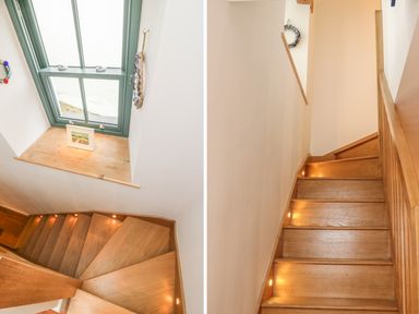 A wooden staircase with built in lights and a teal window above at Lantern Cottage in Padstow