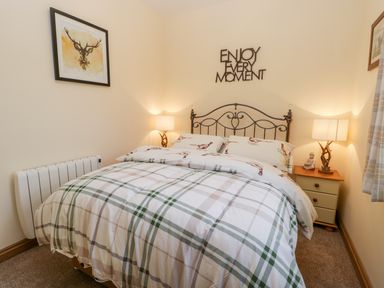 A bedroom with a bed with plaid bedding and wall decor at Wagtail Nest Northfield Cottage in Scalby