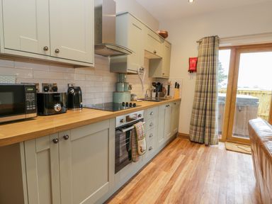 A kitchen with cabinets and wooden countertop and appliances next to a sliding glass door at Wagtail Nest Northfield Cottage Scalby