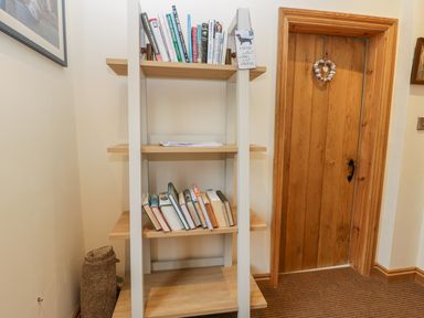 A wooden bookshelf with books next to a wooden door in a corner of a room at Wagtail Nest Northfield Cottage Scalby