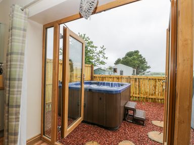 An outdoor patio area with a hot tub fenced yard and stepping stones at Wagtail Nest Northfield Cottage in Scalby