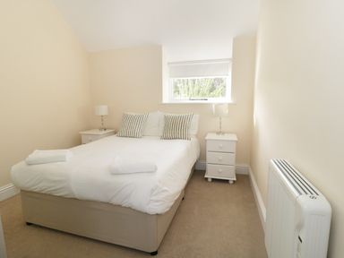 A bedroom with a double bed two bedside tables with lamps and a window at Orchard Cottage in Shaftesbury