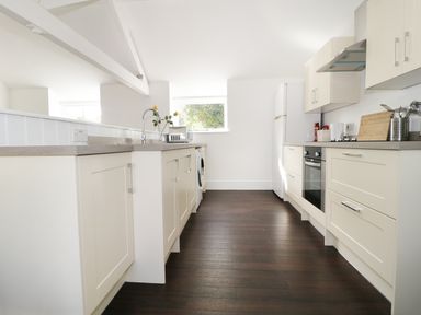 A kitchen with white cabinets a sink refrigerator oven and microwave at Orchard Cottage in Shaftesbury