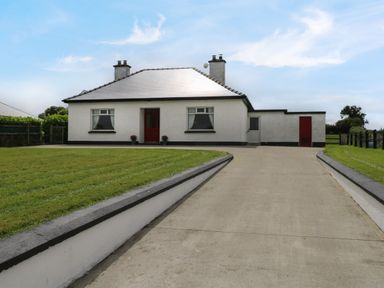A single story house with two chimneys and a concrete driveway at Kates Cottage near Ballina County Mayo