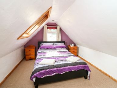 A bedroom with a bed and two bedside tables in an attic room with sloped ceilings at The Hen Pen in Star near Cenarth