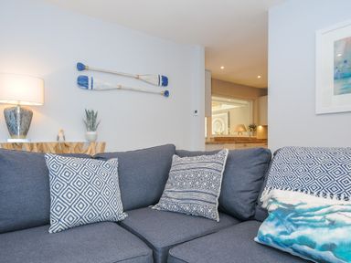 A living room with a blue sofa and patterned cushions with paddles on the wall at Coastal Haven in Crackington near Crackington Haven