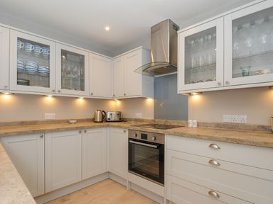A kitchen with white cabinets a stove a toaster and a kettle at Coastal Haven in Crackington near Crackington Haven