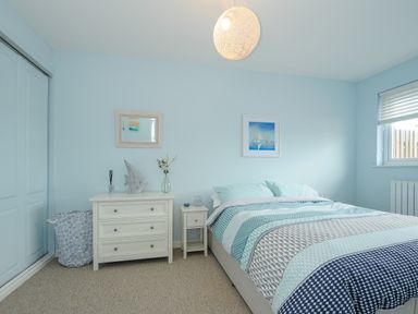 A bedroom with a bed a bedside table a chest of drawers and a window at Coastal Haven in Crackington near Crackington Haven