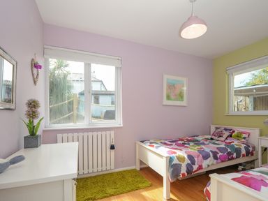 A bedroom with two single beds with colorful bedding a window and a white dresser at Coastal Haven in Crackington near Crackington Haven