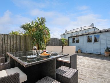 An outdoor patio with a glass top dining table set with plates cups and croissants at Coastal Haven in Crackington near Crackington Haven