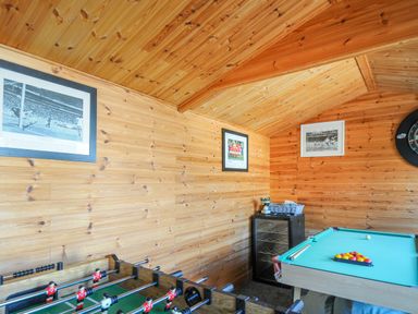 A game room with a foosball table and a pool table with cues on top at Coastal Haven in Crackington near Crackington Haven