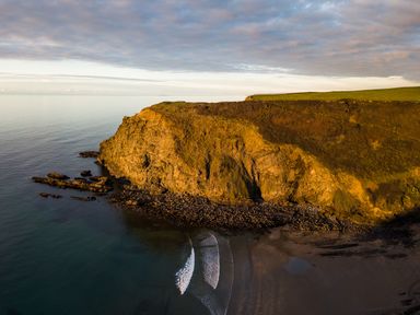 A coastal cliff with rocky shoreline and calm sea at Coastal Haven in Crackington near Crackington Haven