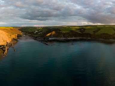A coastal landscape with cliffs fields and a small settlement at Coastal Haven in Crackington near Crackington Haven