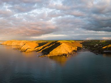 A coastline with cliffs and green fields near water at Coastal Haven in Crackington near Crackington Haven