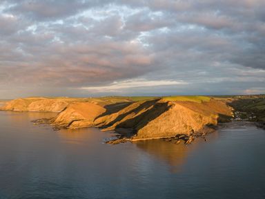 A coastal landscape with cliffs and calm sea under a cloudy sky at Coastal Haven in Crackington near Crackington Haven