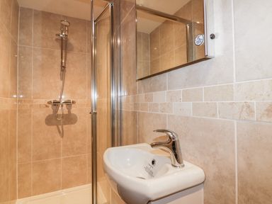 A bathroom with a shower enclosure and a wall mounted sink at The Crows Nest in Mevagissey