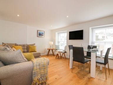 A living room with sofas and a dining table with chairs at The Crows Nest in Mevagissey