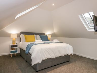 A bedroom with a bed with pillows and folded towels bedside lamps a nightstand and a window at Captain's Cabin in Mevagissey