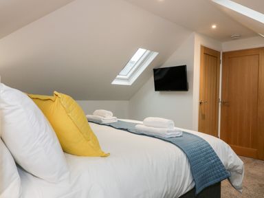A bedroom with a bed with yellow pillows and white linens and two wooden doors at Captains Cabin in Mevagissey