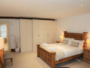A bedroom with a wooden bed frame bedside tables lamps and cream wardrobes at The Penthouse Lynmouth Bay in Lynton
