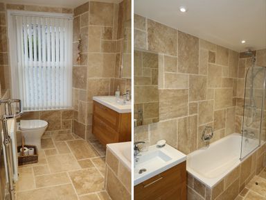 A bathroom with beige tiled walls and floor featuring a toilet, a wooden vanity with sink, a bathtub with shower and glass screen at The Penthouse Lynmouth Bay in Lynton