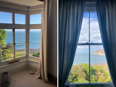 Two views of ocean and coastline seen through windows with curtains at The Penthouse Lynmouth Bay in Lynton
