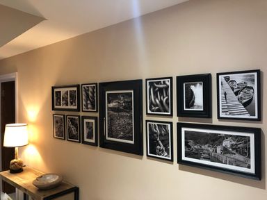 A hallway with framed black and white photographs on the wall and a lamp on a wooden table at The Penthouse Lynmouth Bay in Lynton