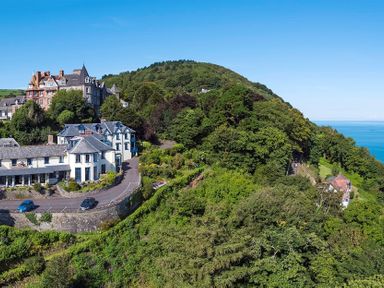 A hillside with houses surrounded by trees and greenery near the coast at The Penthouse Lynmouth Bay in Lynton