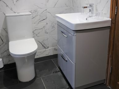 A bathroom with a white toilet and a sink with two drawers and two glasses on the counter at The Penthouse Lynmouth Bay in Lynton