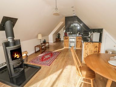 A kitchen and dining area with a wood burning stove and wooden furniture at The Lookout in Llangrove
