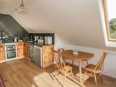 A kitchen with wooden cabinets a dining table with two chairs and a large skylight window at The Lookout in Llangrove