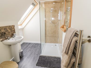 A bathroom with a shower enclosure sink towels and a skylight window at The Lookout in Llangrove