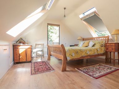 A bedroom with a wooden bed yellow bedding rugs and skylights at The Lookout in Llangrove