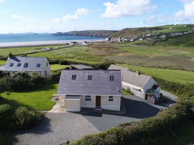Houses near a beach and green fields with hills in the background at Bramble Cottage in Newgale