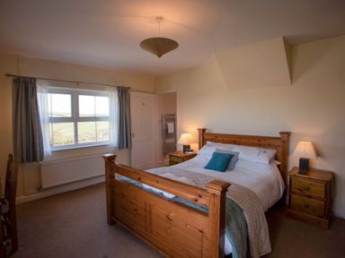 A bedroom with a wooden bed and two bedside tables with lamps at Bramble Cottage in Newgale