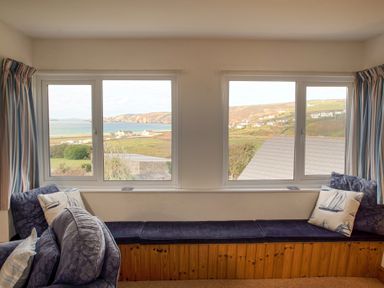 A window seat with cushions and a view of the countryside and sea at Bramble Cottage in Newgale
