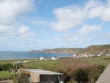 A coastal landscape with houses fields and cliffs by the sea at Bramble Cottage in Newgale