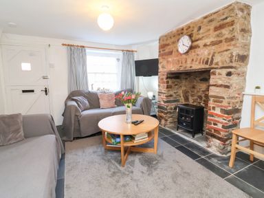 A living room with a sofa, coffee table, and fireplace at Willets Cottage in Appledore