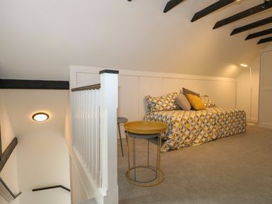 An attic room with a patterned sofa bed cushions side table and a floor lamp at Thames Reach in Wallingford