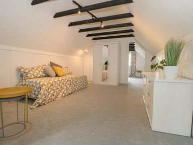 A bedroom with a patterned bed and pillows next to a white wardrobe and a dresser with plants at Thames Reach in Wallingford