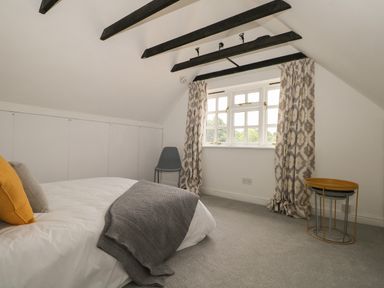A bedroom with a bed pillows and blanket a chair window with curtains and nested tables at Thames Reach in Wallingford